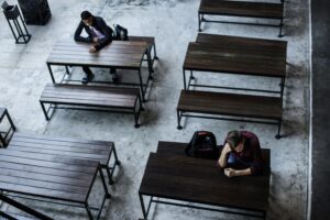 Un étudiant seul à une table dans une ambiance morose